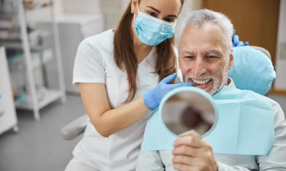 Man looking in mirror smiling at new teeth